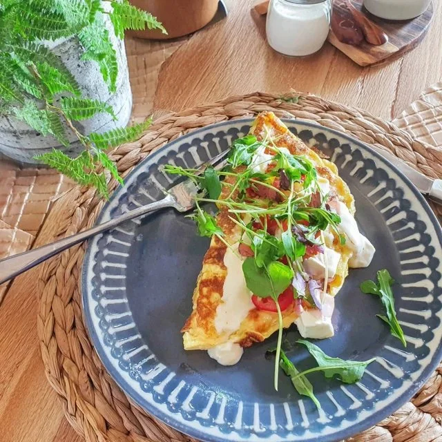 Kruidenomelet met geitenkaas op een bord, geserveerd met verse kruiden.