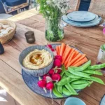 Mediterrane antipasti-plank met romige hummus, verse jonge wortelen en knapperige sugarsnaps